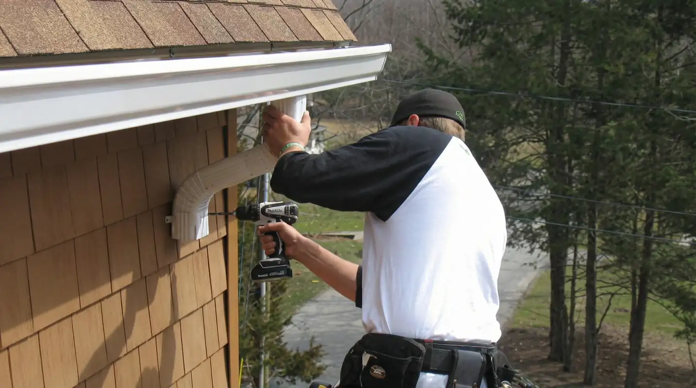Professional contractor installing tan vinyl siding panels on a residential home exterior in Dayton, OH